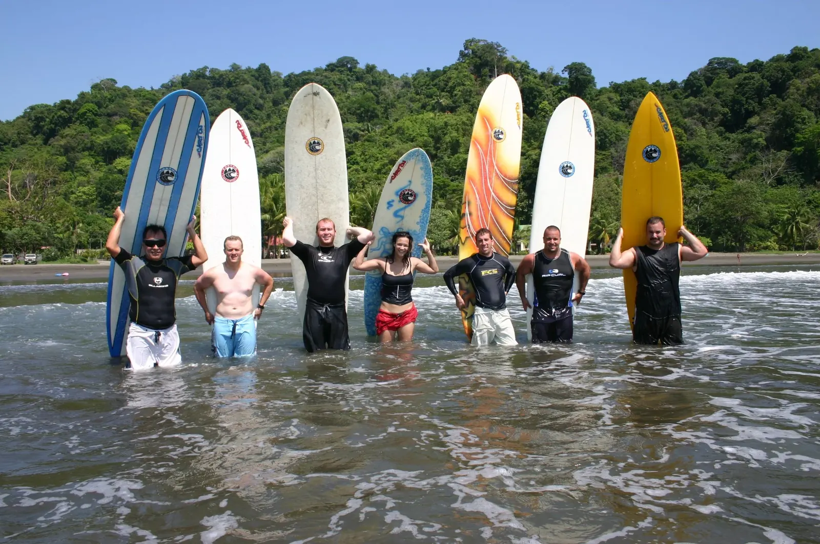 A surf camp group standing in the shallows with their boards